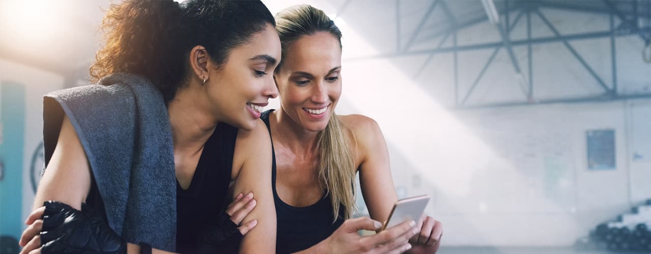 two-women-gym-looking-at-smartphone
