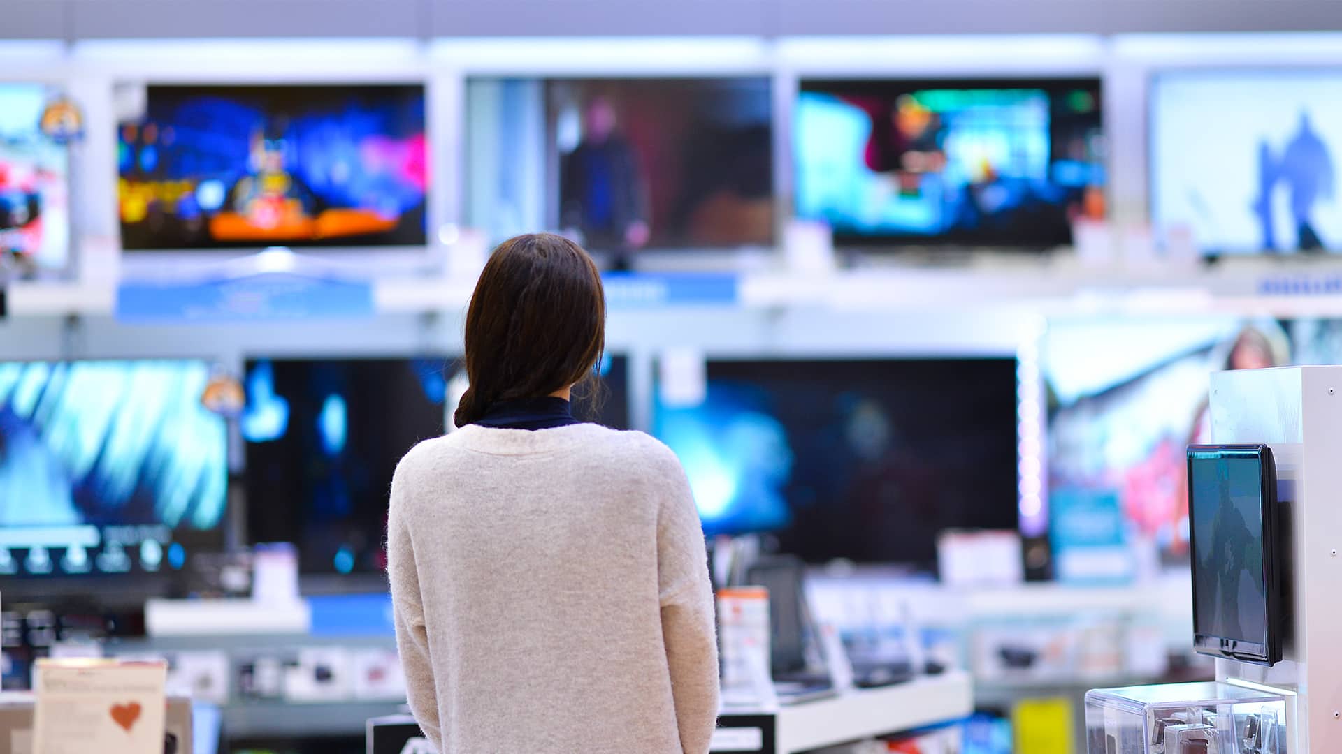 woman standing in front of wall of technology tvs shopping new 2020 hero