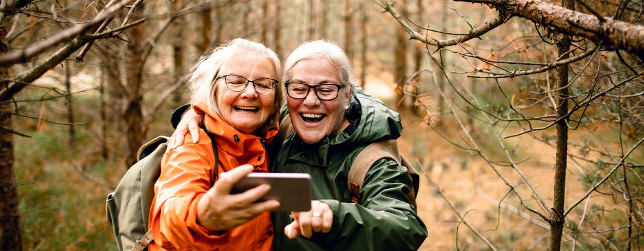 Close up of two female seniors taking a selfie while hiking in the forest