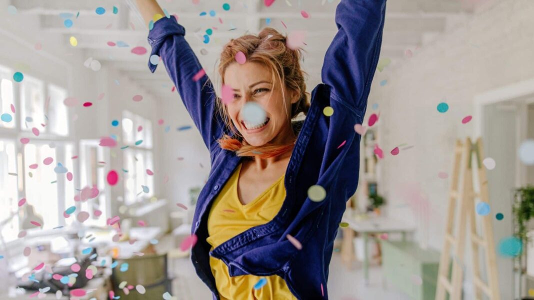 Photo of a young woman celebrating her youth, beauty, and femininity - dancing while confetti is falling.