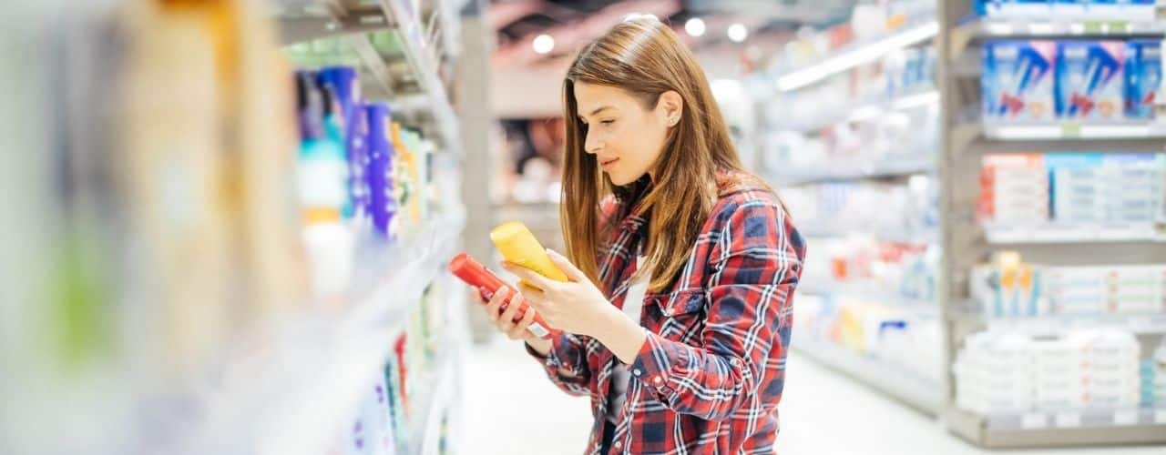 young woman comparing two cosmetic products in the drugstore aisle of the grocery store