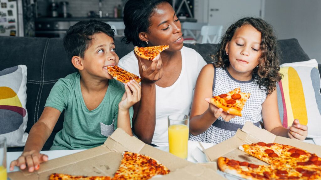family eating pizza while sitting on sofa at home