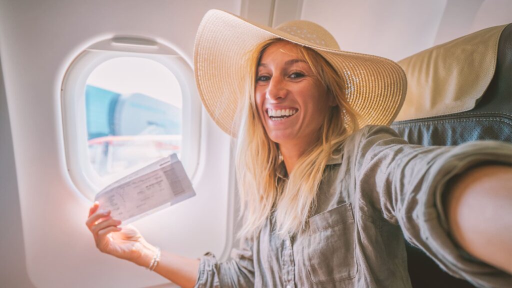 hero Young woman in airplane takes mobile phone selfie portrait during flight