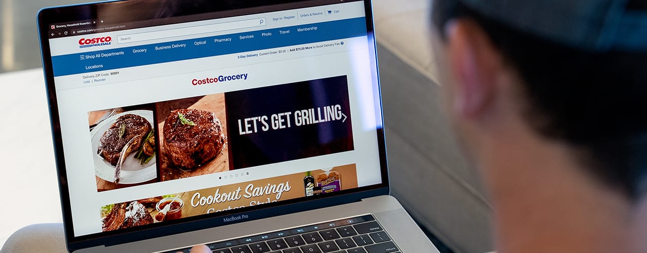 man sitting in front of laptop looking at costco grocery website macbook slickdeals
