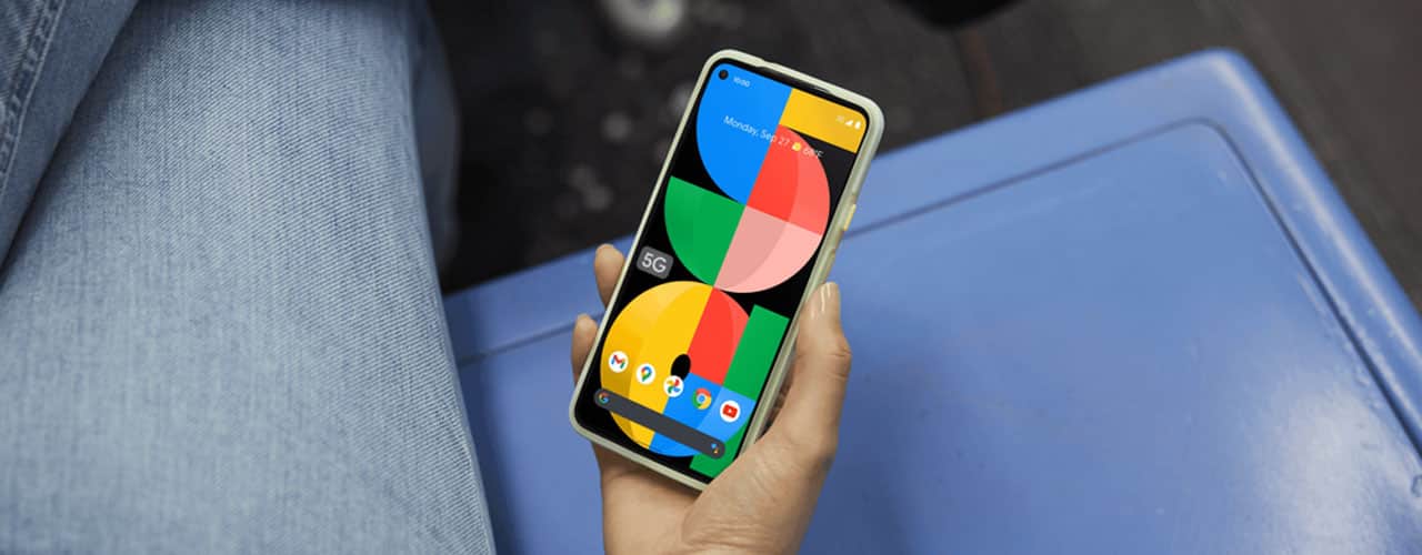 google pixel 5a held in someones hand over a blue chair