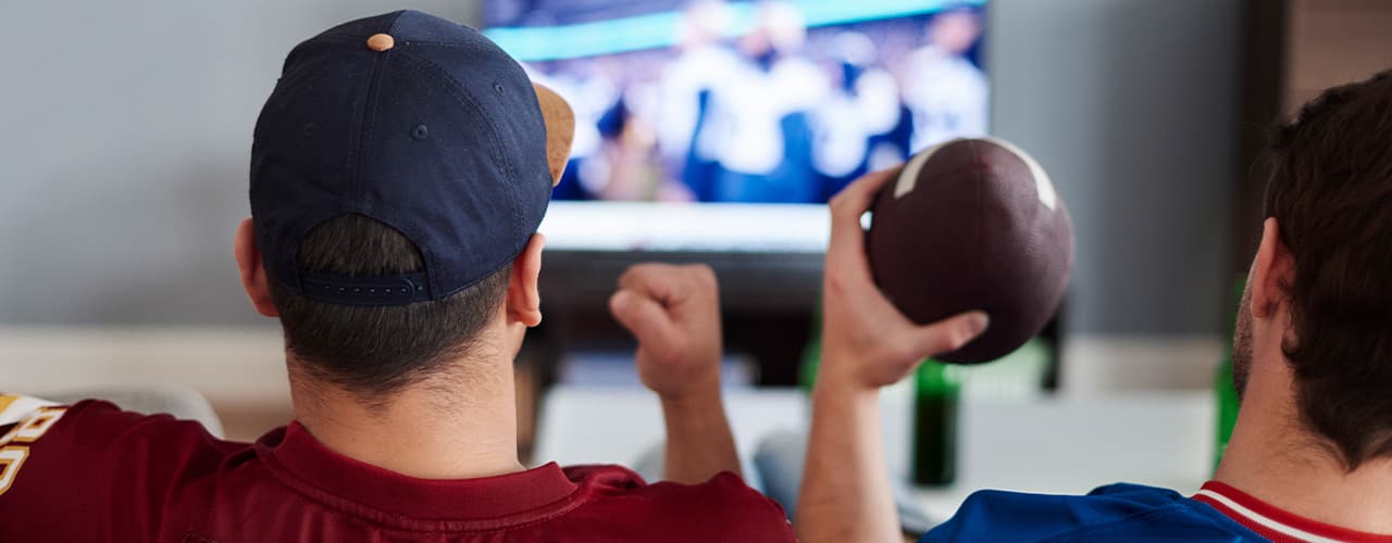 two men happy and watching a football game on tv