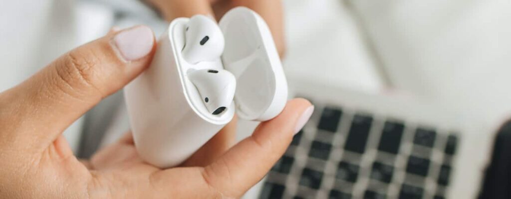 person holding airpods over iMac