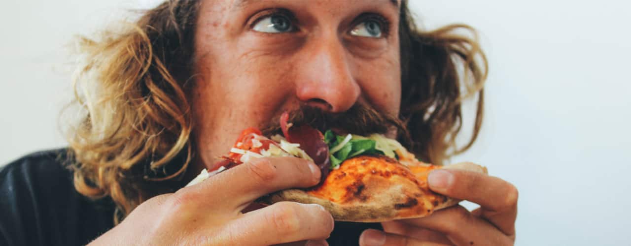 close up of man eating pizza
