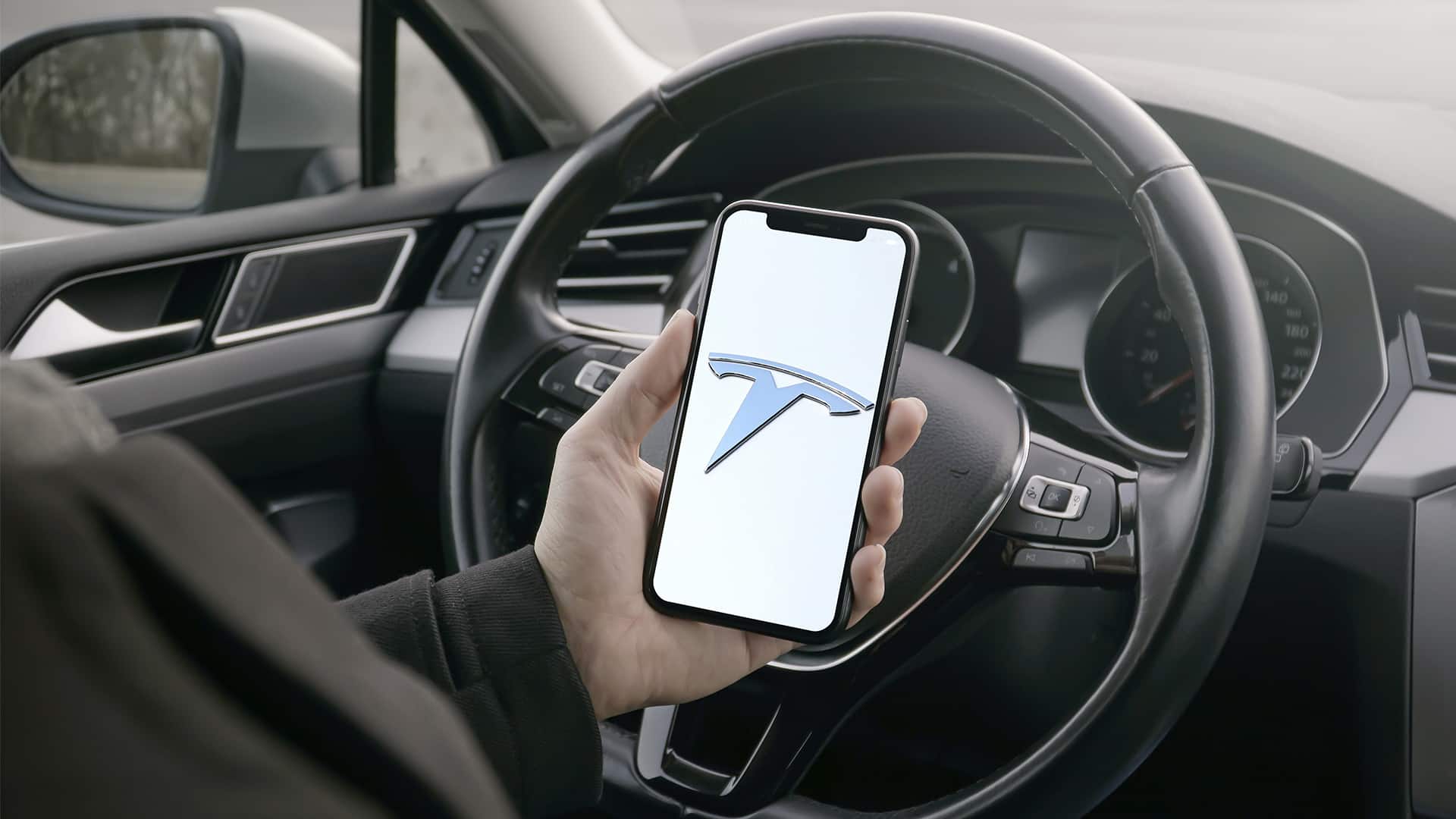 Tesla logo on smartphone in car