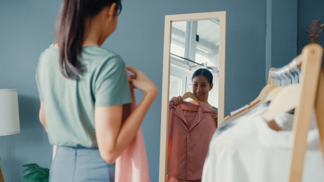 woman trying on clothes in mirror at home