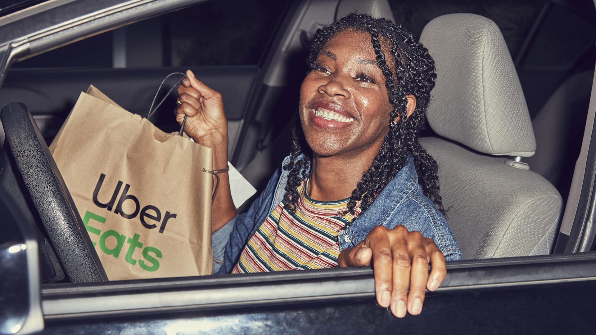 woman in car with uber eats bag