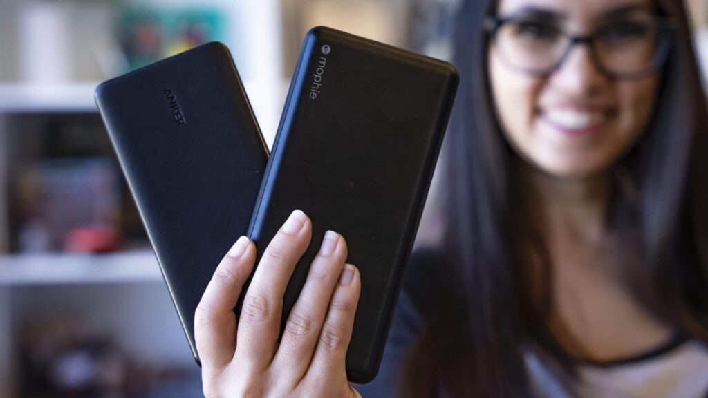 anker and mophie power banks held in one hand with $22 and $80 prices marked on them hero
