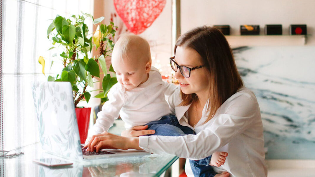 mom holding baby while searching on computer