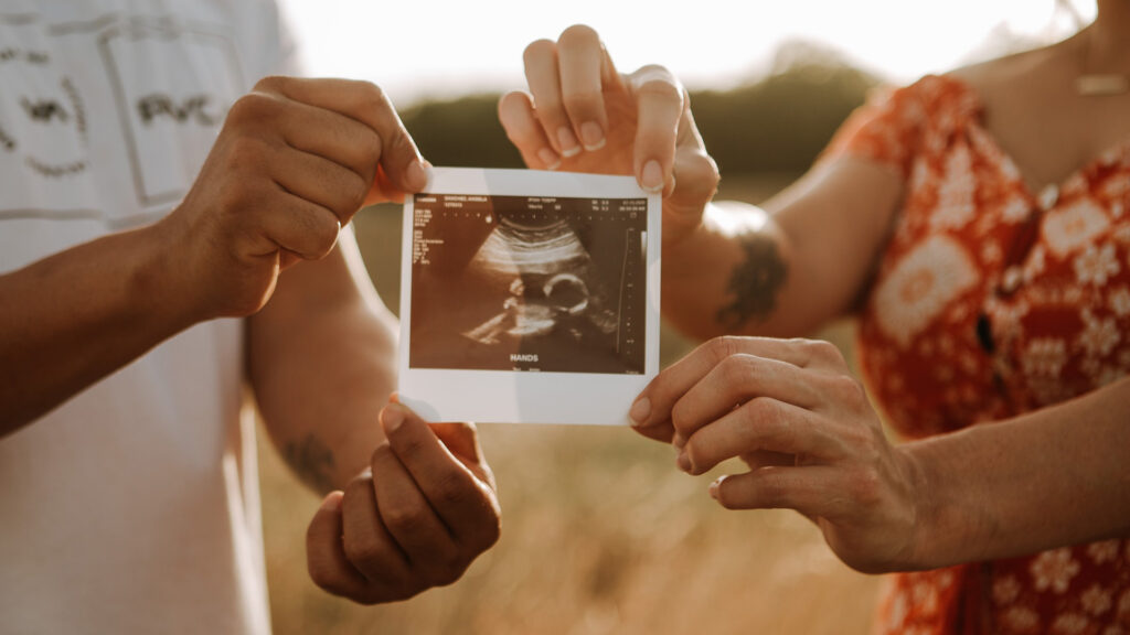 parents to be holding ultrasound photo during maternity shoot