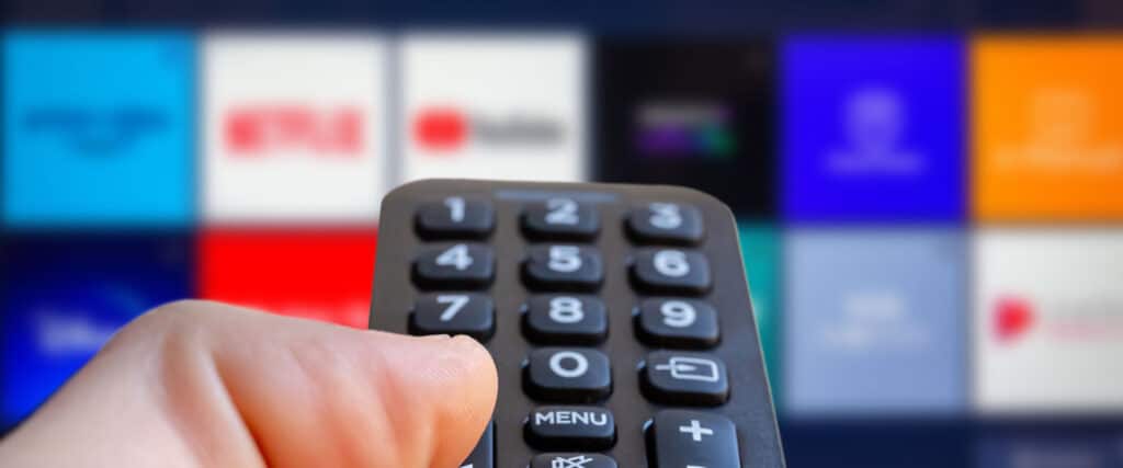 hand on remote watching streaming tv