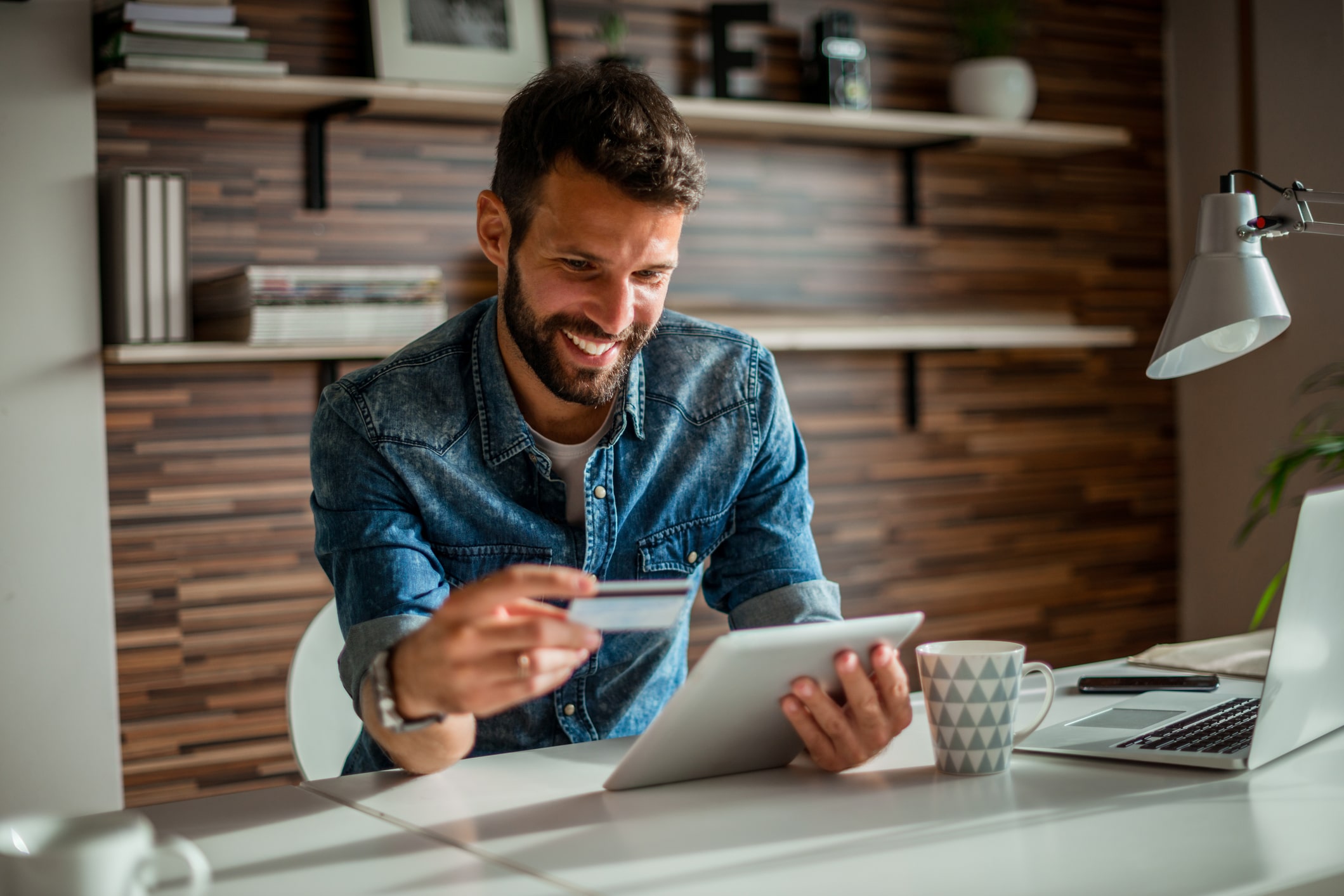 Man holding credit card while using digital tablet in the office.