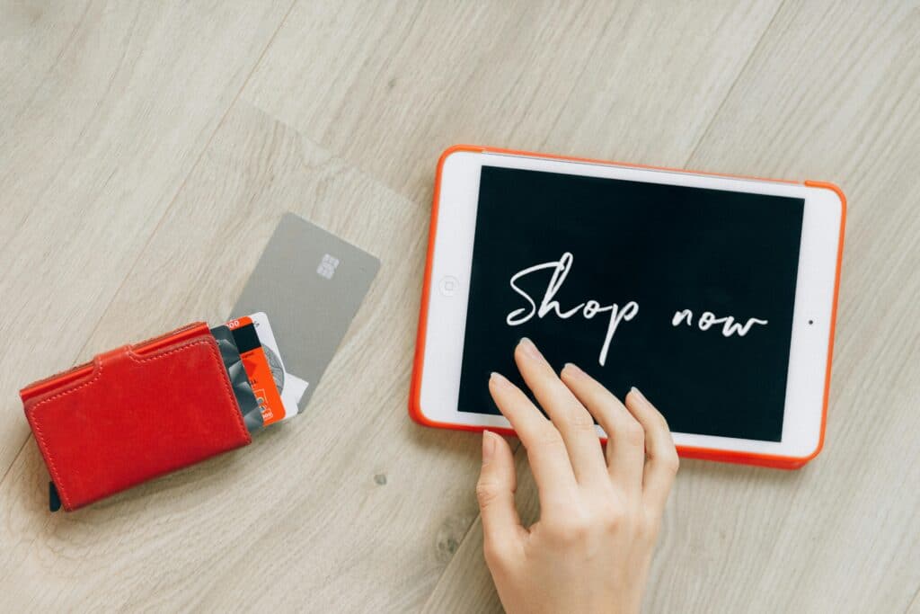 Tablet with the text shop now, a hand and a wallet