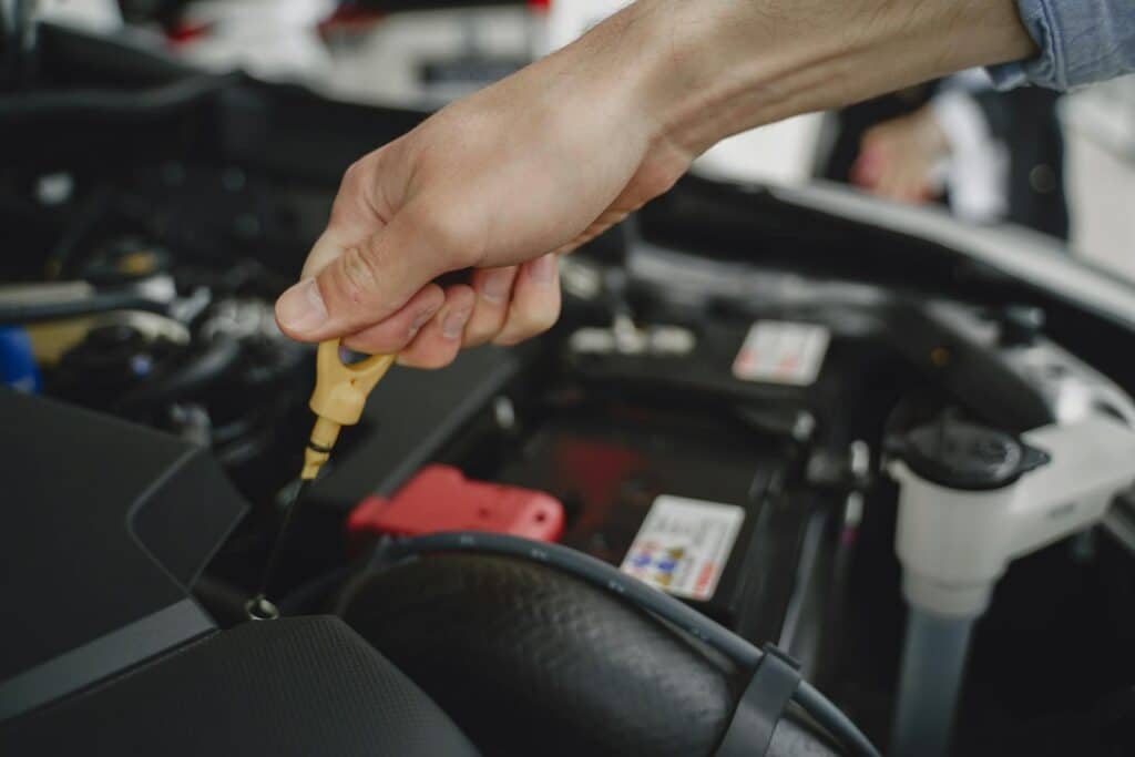 Hand pulling out oil stick to check oil on a car