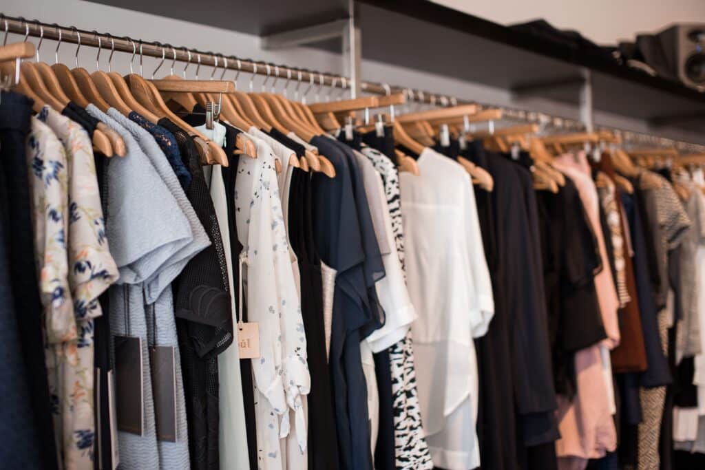 clothing hanging on wooden hangers displaying various styles and colors.